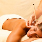 Frau mit Ohrenkerze und Edelstein Massage Frau mit Ohrenkerze und Edelstein Massage